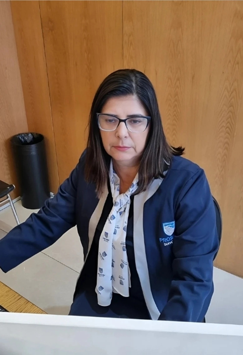 Funcionária da Proserv uniformizada atuando em escritório, focada nas tarefas administrativas e atendimento interno.
