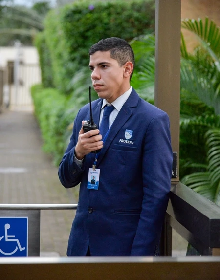 Profissional de segurança uniformizado da Proserv realizando vigilância em área externa de empresa.