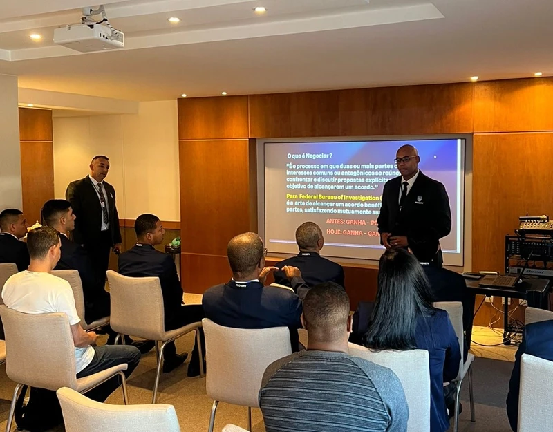 Palestrante conduzindo capacitação empresarial para equipe de profissionais em sala de treinamento.